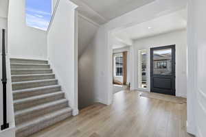 Foyer entrance with light wood finished floors, recessed lighting, stairs, and baseboards