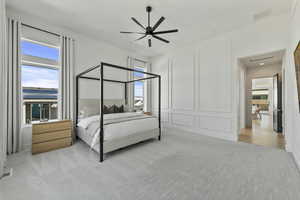 Bedroom featuring visible vents, attic access, light carpet, a decorative wall, and a ceiling fan