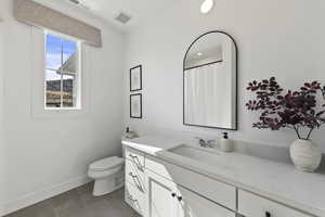 Bathroom featuring vanity, visible vents, baseboards, tile patterned flooring, and toilet