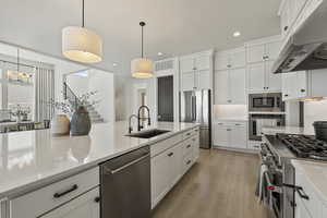 Kitchen featuring a sink, decorative backsplash, stainless steel appliances, and under cabinet range hood adn under cabinet lighting