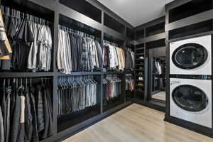 Walk in closet with wood finished floors and stacked washer / dryer
