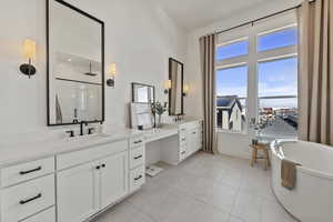 Full bath with vanity, baseboards, a stall shower, a freestanding bath, and tile patterned floors