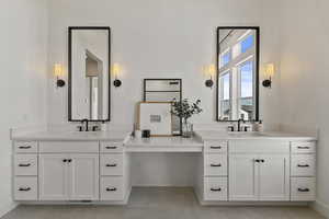 Bathroom with a sink, baseboards, and two vanities