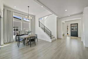 Dining space with baseboards, light wood finished floors, recessed lighting, stairs, and a notable chandelier