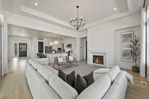 Main Level Living room with light wood finished floors, recessed lighting, a fireplace, and a raised ceiling