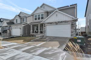 Craftsman-style home with stone siding, stucco siding, board and batten siding, and driveway
