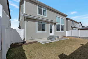 Back of house with stucco siding, a gate, fence, a yard, and a patio area
