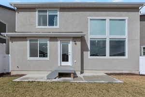 Rear view of house featuring a patio area, stucco siding, and a yard