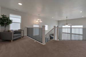 Hallway featuring visible vents, an upstairs landing, recessed lighting, an inviting chandelier, and carpet flooring
