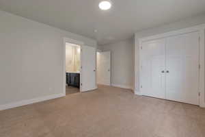 Unfurnished bedroom featuring baseboards, a closet, and light carpet
