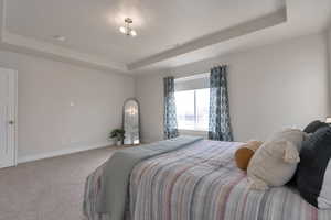 Carpeted bedroom with baseboards, a raised ceiling, and visible vents