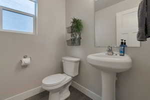 Half bath with a sink, baseboards, and toilet