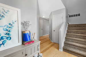 Stairs featuring wood finished floors, visible vents, and baseboards
