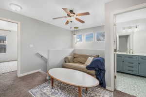 Living area with baseboards, an upstairs landing, light carpet, and ceiling fan