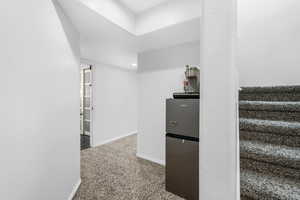 Interior space featuring carpet, baseboards, and freestanding refrigerator