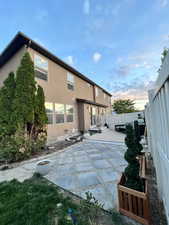 Back of house at dusk with a patio area, stucco siding, and a fenced backyard