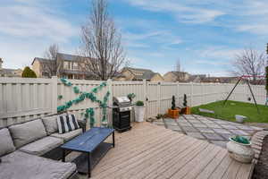 Deck with area for grilling, a lawn, an outdoor hangout area, and a fenced backyard