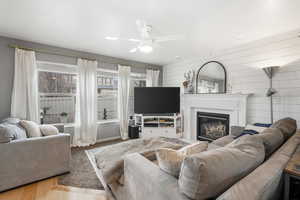 Living room featuring a glass covered fireplace, wood finished floors, and a ceiling fan