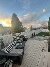 Deck at dusk with area for grilling, a fenced backyard, and an outdoor hangout area