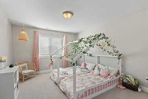 Bedroom featuring baseboards, light colored carpet, visible vents, and a textured ceiling