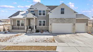 View of front of house featuring driveway, an attached garage, a shingled roof, stone siding, and board and batten siding