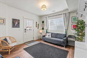 Living area featuring visible vents, baseboards, a textured ceiling, and wood finished floors