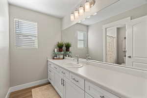 Full bath with baseboards, toilet, wood finished floors, and vanity