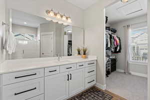 Primary ensuite full bath with a walk in closet, wood finished floors, a shower stall, and vanity