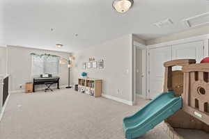 Recreation room featuring visible vents, carpet floors, a textured ceiling, and baseboards