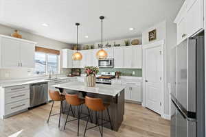 Kitchen with a sink, a breakfast bar area, light wood-style floors, and stainless steel appliances