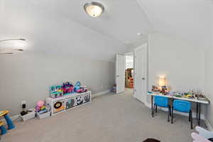 Rec room with baseboards, carpet flooring, a textured ceiling, and lofted ceiling
