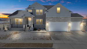 View of front of house featuring stone siding, covered porch, board and batten siding, and driveway