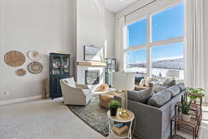 Carpeted living room with baseboards, a high ceiling, and a glass covered fireplace