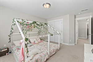 Carpeted bedroom with baseboards, visible vents, and a closet