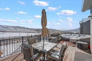 Snow covered deck featuring a mountain view and outdoor dining space