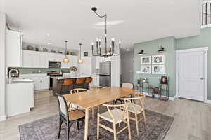 Dining room featuring recessed lighting, baseboards, light wood finished floors, and a chandelier