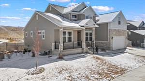 View of front of home with board and batten siding, concrete driveway, fence, and stone siding
