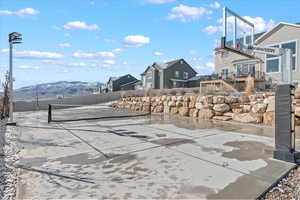 View of patio with a tennis court and fence
