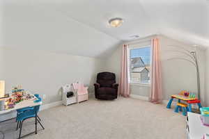 Playroom with lofted ceiling, baseboards, carpet floors, and a textured ceiling