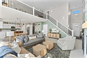 Living area with an inviting chandelier, stairway, and a towering ceiling