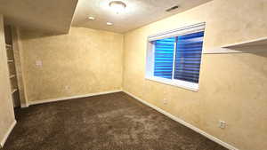 Carpeted spare room featuring visible vents, baseboards, and a textured ceiling