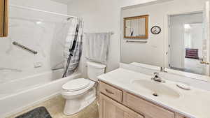 Full bathroom with toilet, vanity, and shower / bathtub combination with curtain