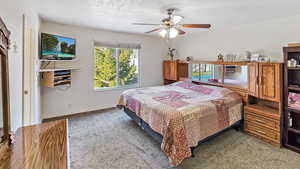 Bedroom featuring ceiling fan, carpet, baseboards, and a textured ceiling