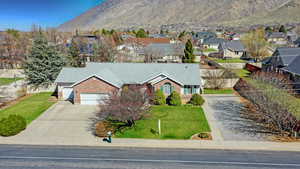 View of front of property with concrete driveway, a front yard, a mountain view, brick siding, and a garage