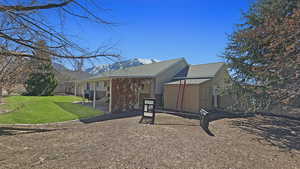 View of home's exterior with a patio area, an outbuilding, brick siding, a storage shed, and a yard