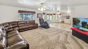 Living area featuring light carpet, a ceiling fan, french doors, and a textured ceiling