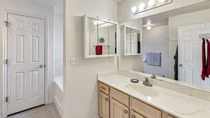 Full bath with tile patterned flooring, vanity, and a tub to relax in