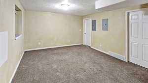 Empty room featuring electric panel, visible vents, carpet floors, and a textured ceiling