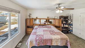 Carpeted bedroom featuring ceiling fan, baseboards, visible vents, and a textured ceiling