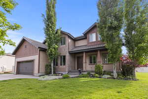 View of front of property featuring concrete driveway, a front lawn, board and batten siding, a garage, and covered porch